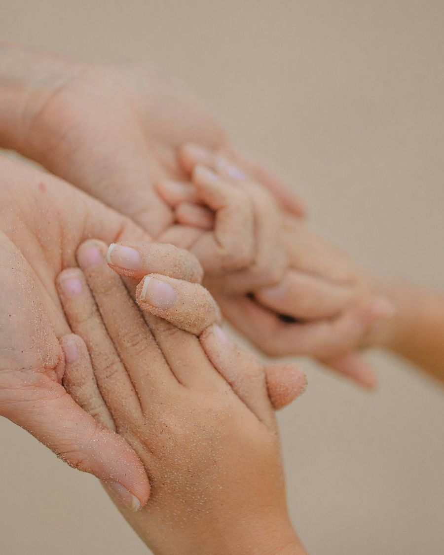 An adult and child gently holding hands