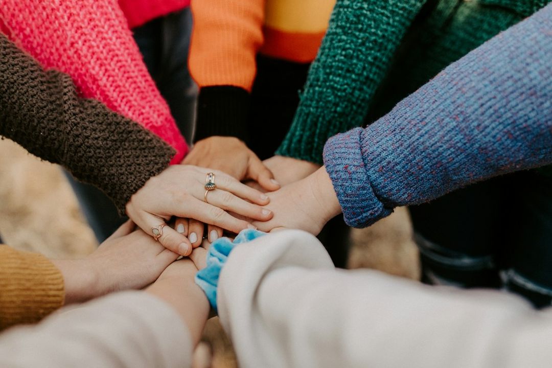 A diverse group stacking their hands together in a circle