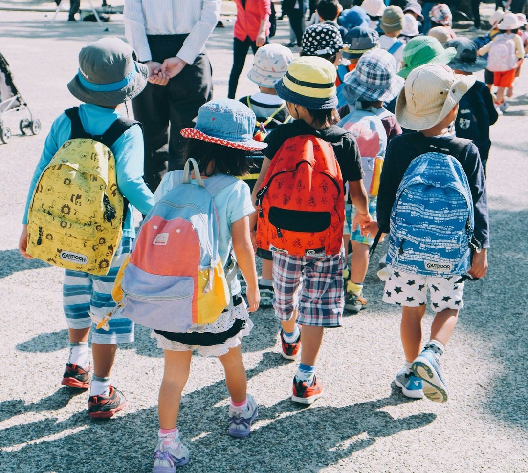 Children walking to school with colorful backpacks