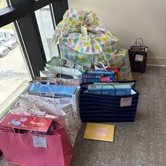 Wrapped gifts and gift bags stacked by a window