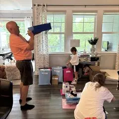 Adults and a young helper sorting birthday gift bags in a living room