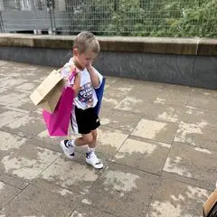 A young boy carrying several gift bags