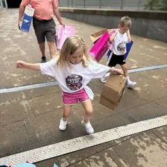 Two young children carrying gift bags, followed by an adult