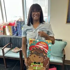 A volunteer holding a birthday gift bag