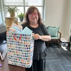 A volunteer holding a birthday gift bag