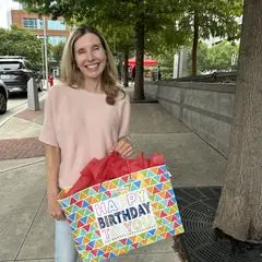 A volunteer holding a birthday gift bag